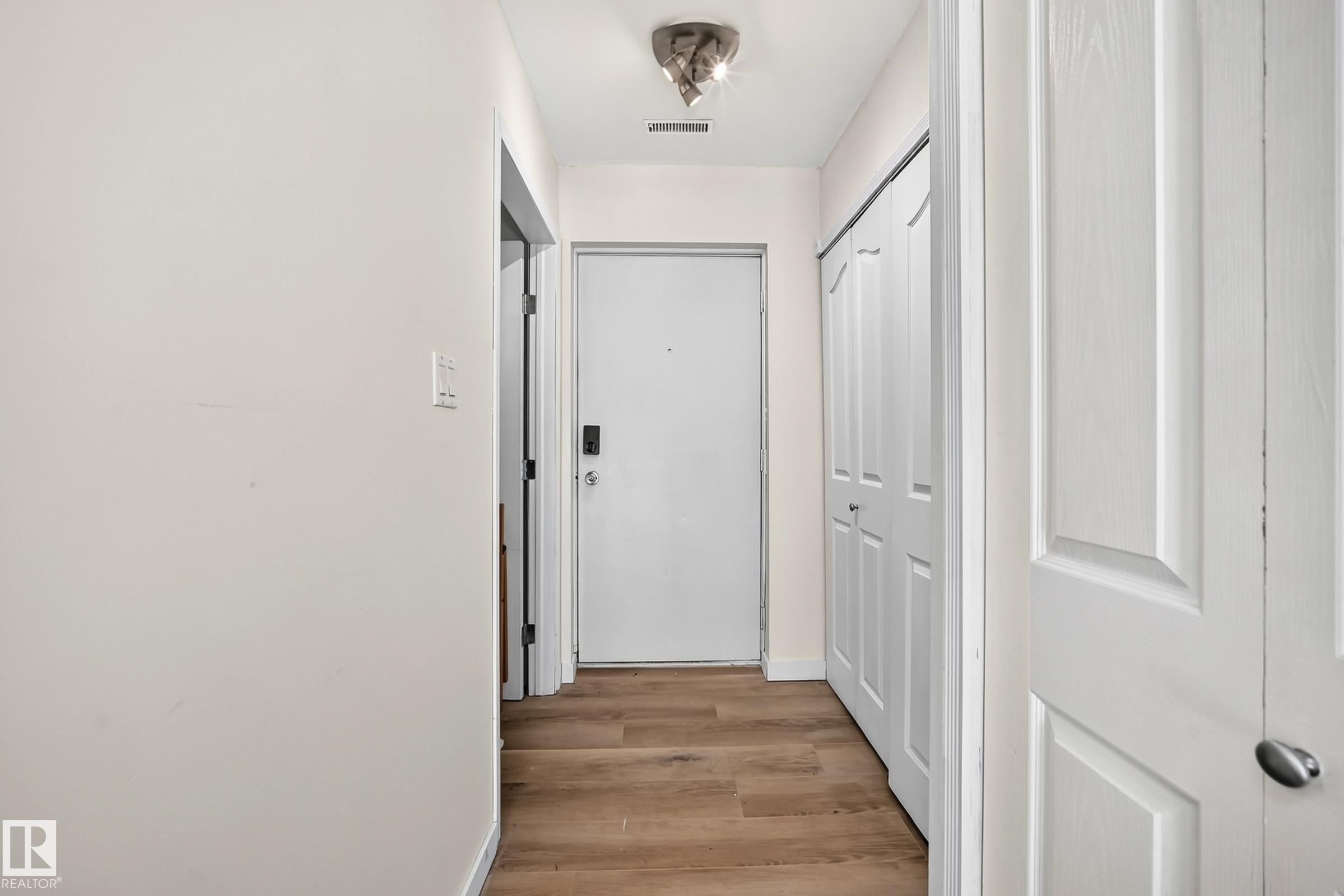 Wood-finish flooring, white paneled bifold doors, and a ceiling-mounted light fixture - 161 Lancaster Terrace Nw, Edmonton, AB
