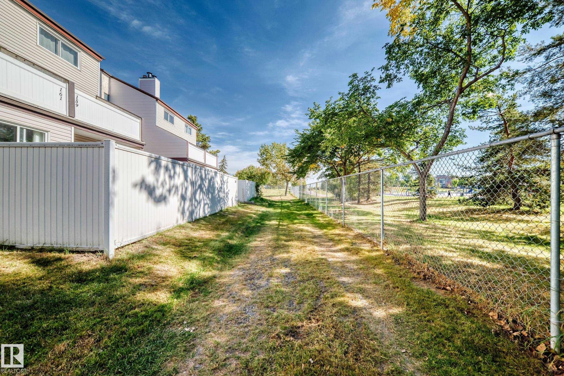 Expansive backyard featuring a manicured lawn, established trees, chain link fencing, and a privacy fence - 161 Lancaster Terrace Nw, Edmonton, AB