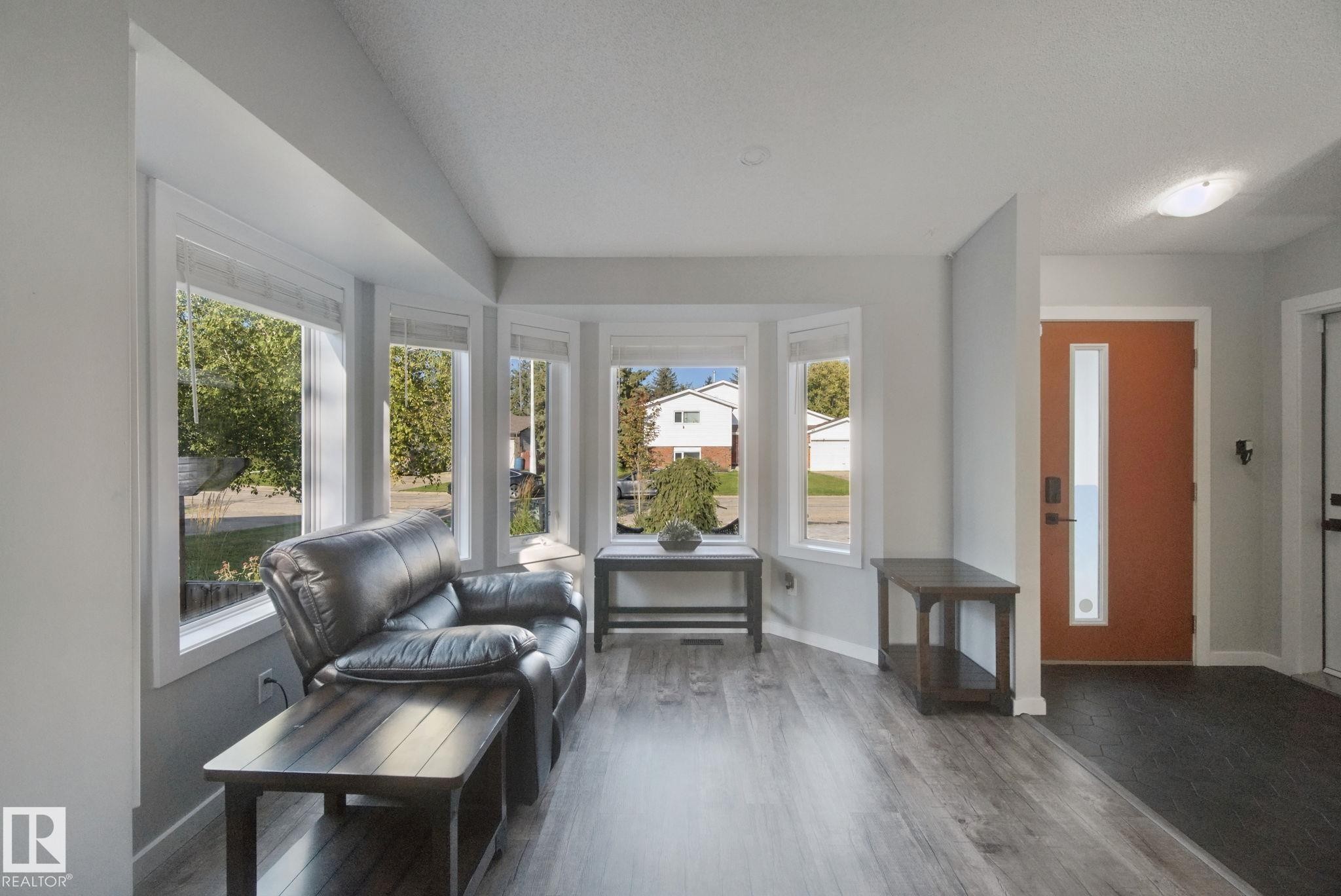 Bay window with multiple panes, wood-finish flooring, recessed lighting, and a front entry door with vertical glass insert - 38 Menalta Place, Cardiff, AB