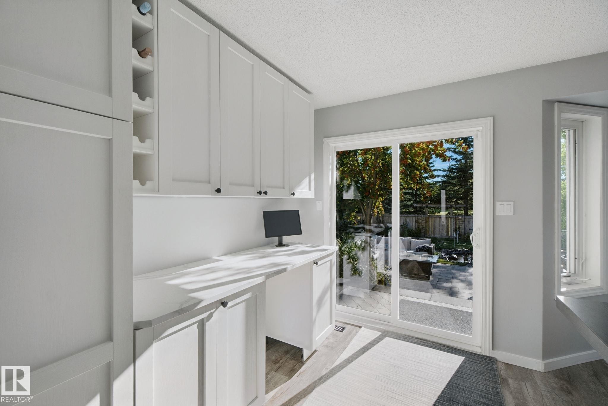 Built-in desk area, white cabinetry, integrated wine storage, sliding glass patio door, and wood-finish flooring - 38 Menalta Place, Cardiff, AB