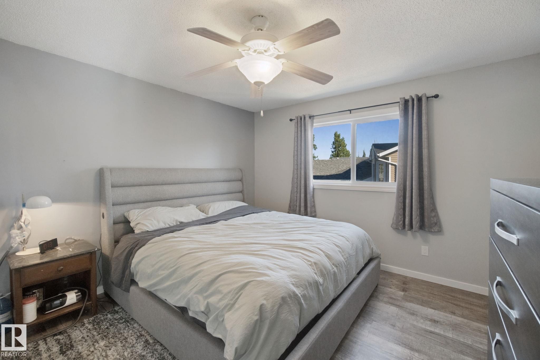 Recessed window with white trim, wood-finish flooring, ceiling fan with integrated lighting, light gray wall tones, and white ceiling - 38 Menalta Place, Cardiff, AB