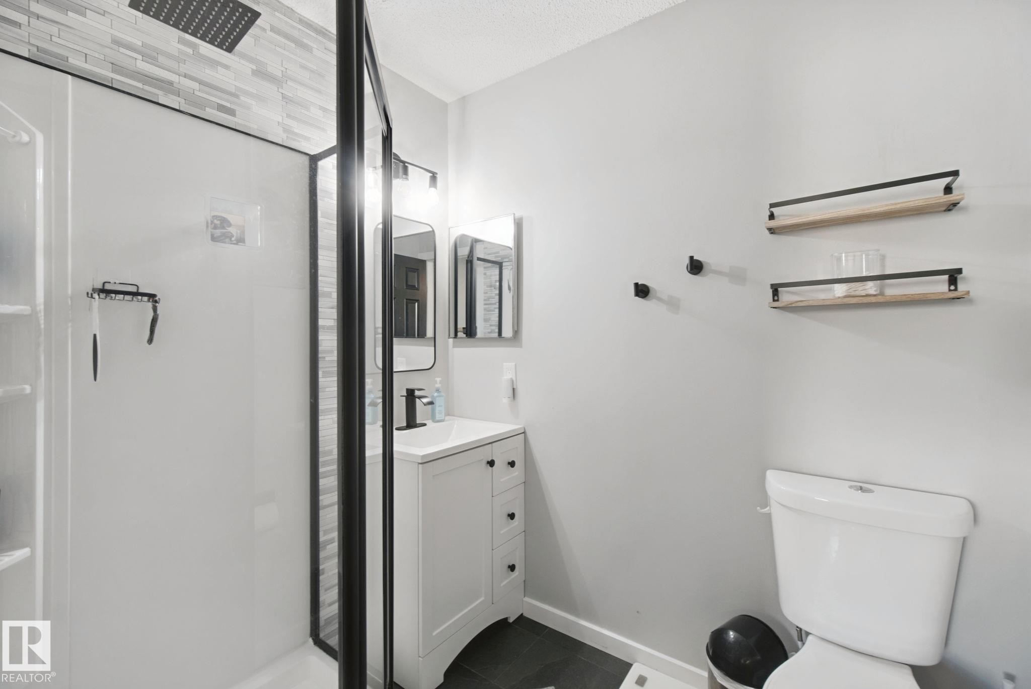 Shower with black framed enclosure, rainfall shower head, and tile surround - 38 Menalta Place, Cardiff, AB