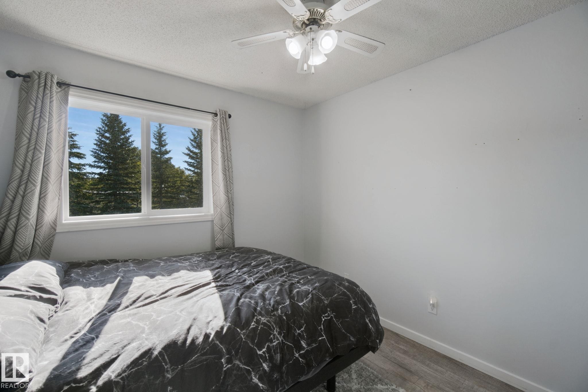 White walls, wood-finish flooring, and a ceiling fan with integrated lighting - 38 Menalta Place, Cardiff, AB