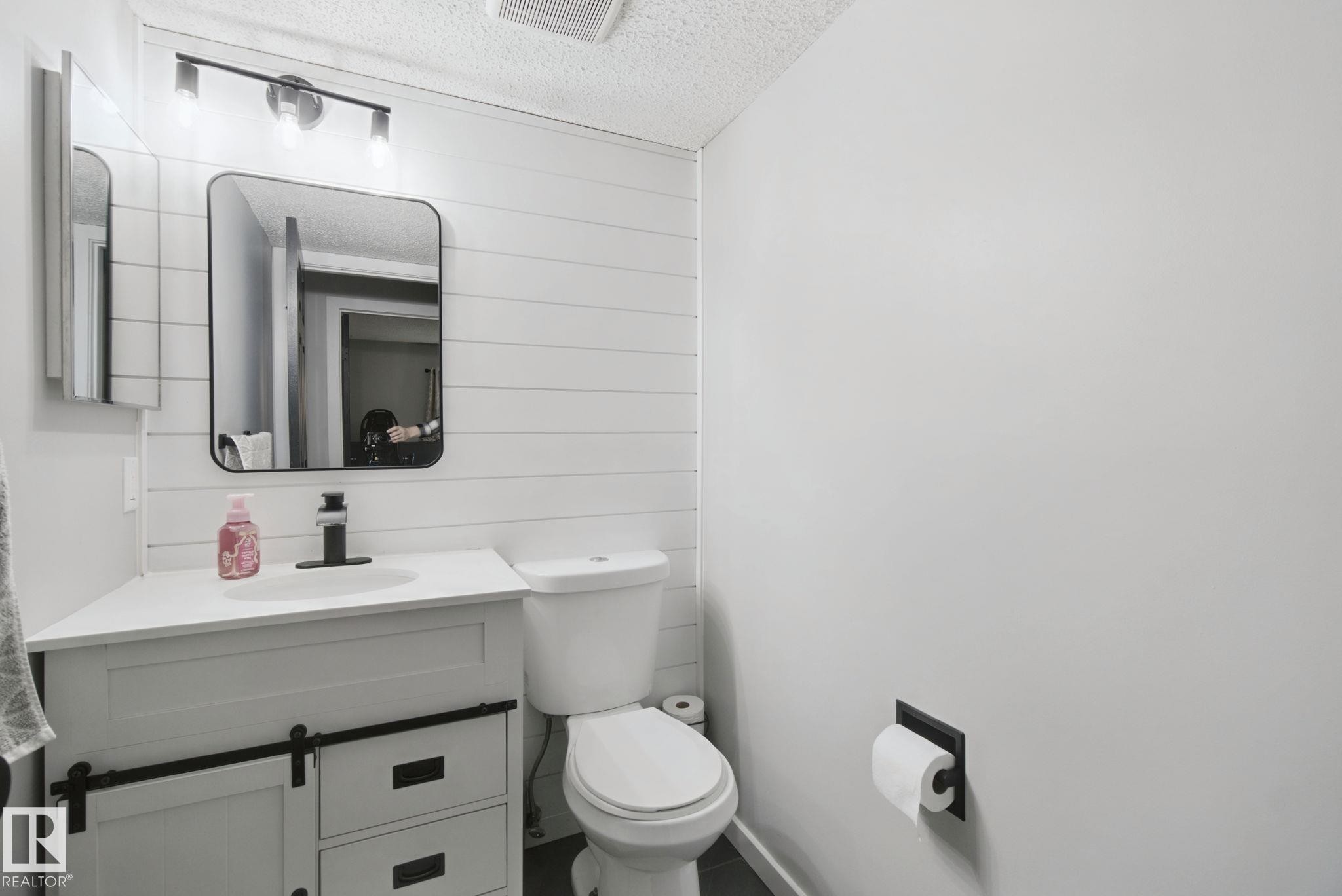Vanity with barn door-style cabinetry, undermount sink, and matte black faucet - 38 Menalta Place, Cardiff, AB