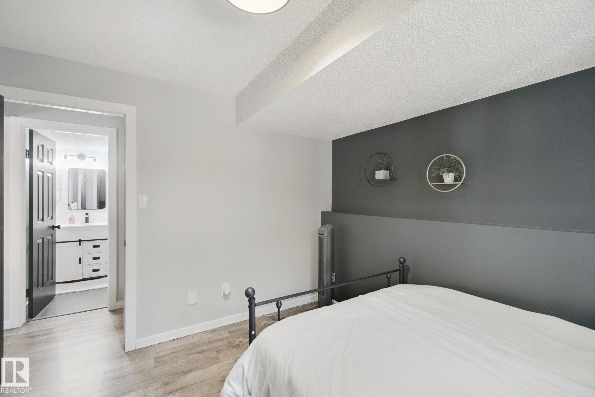 Wood-finish flooring, accent wall, and a full bathroom with a vanity, rectangular sink, and attached mirror - 38 Menalta Place, Cardiff, AB