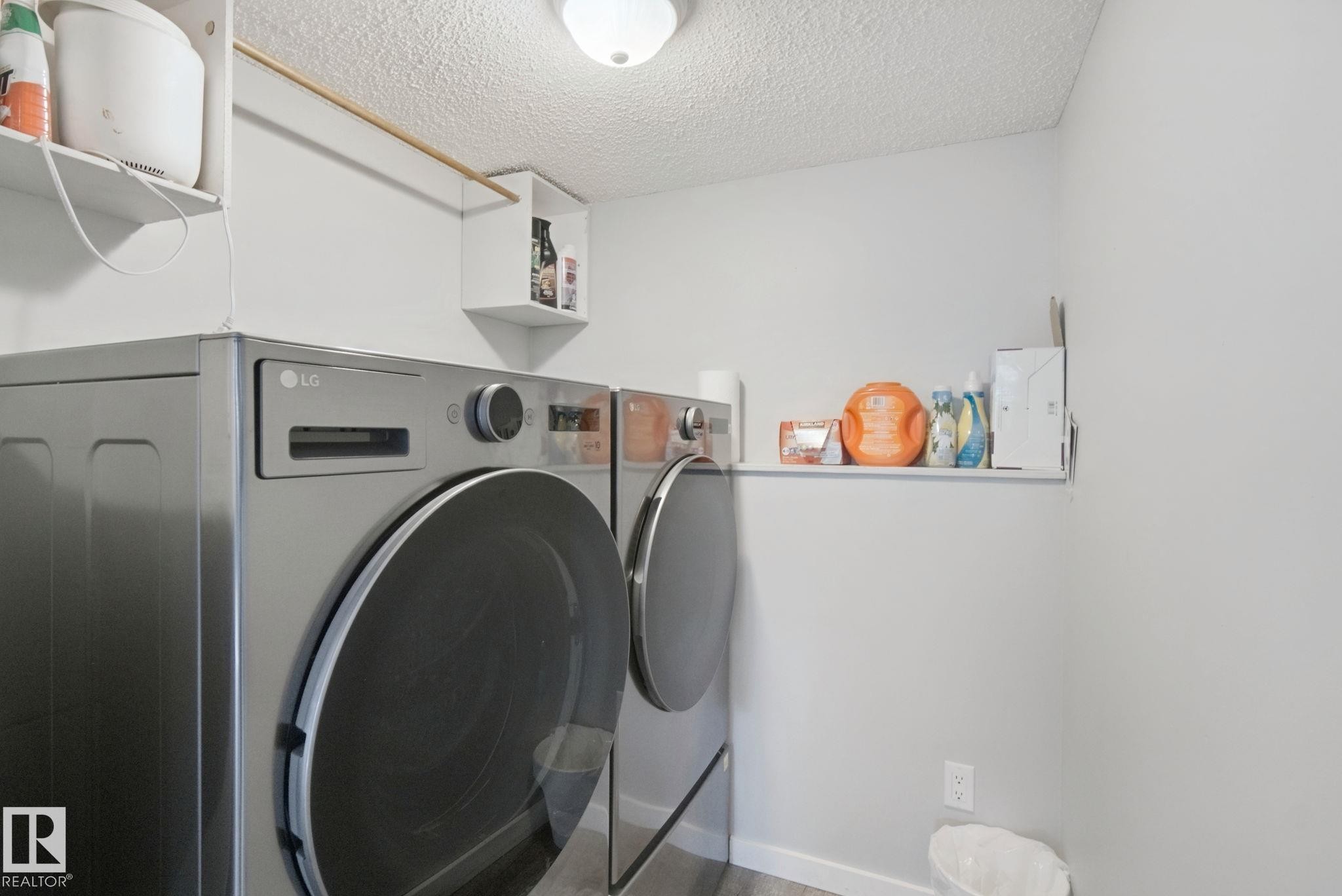 Laundry area with front-loading appliances, white wall shelving, and a hanging rod - 38 Menalta Place, Cardiff, AB