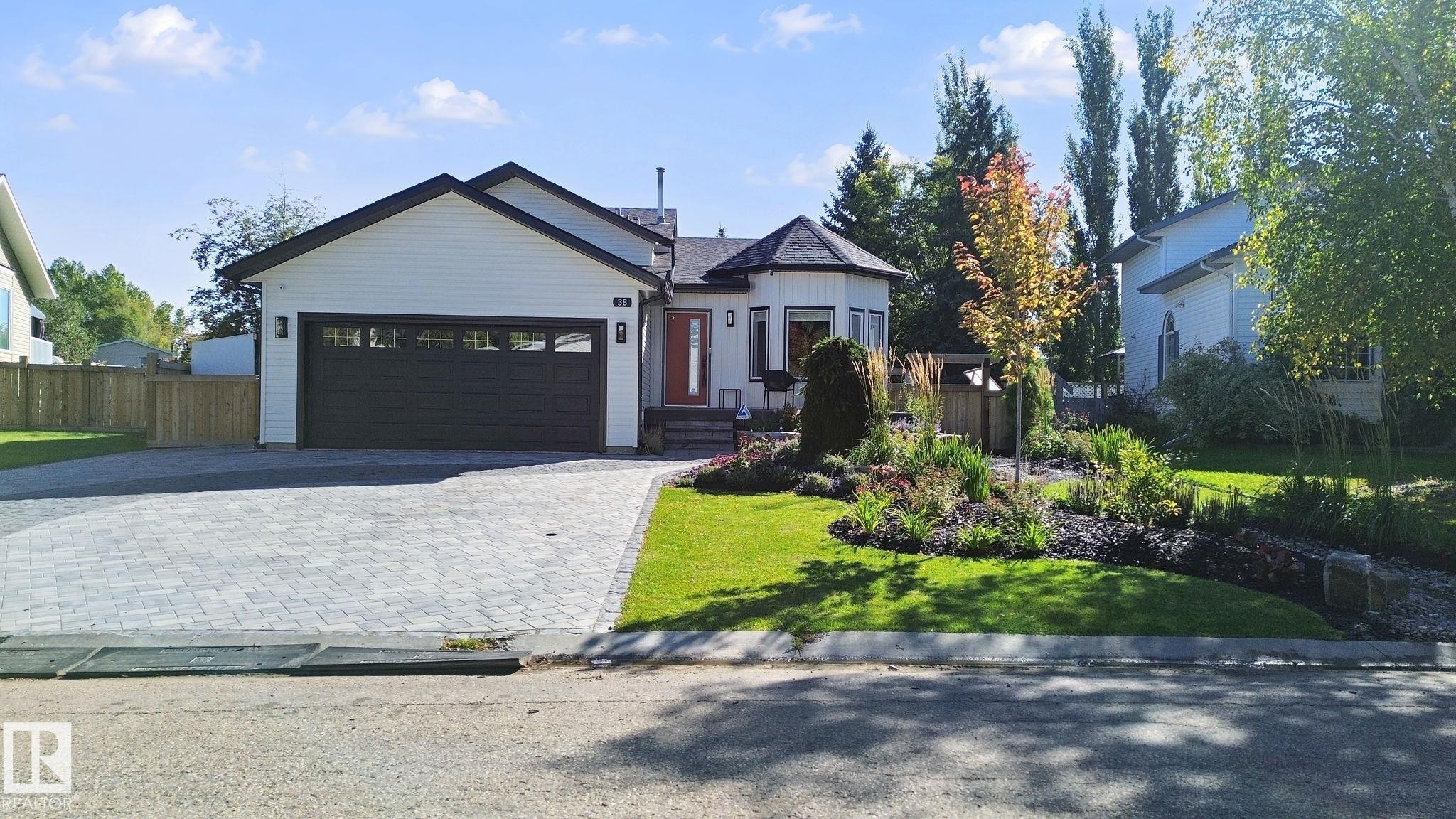 Contemporary exterior with white siding, dark trim, and a prominent dark garage door - 38 Menalta Place, Cardiff, AB