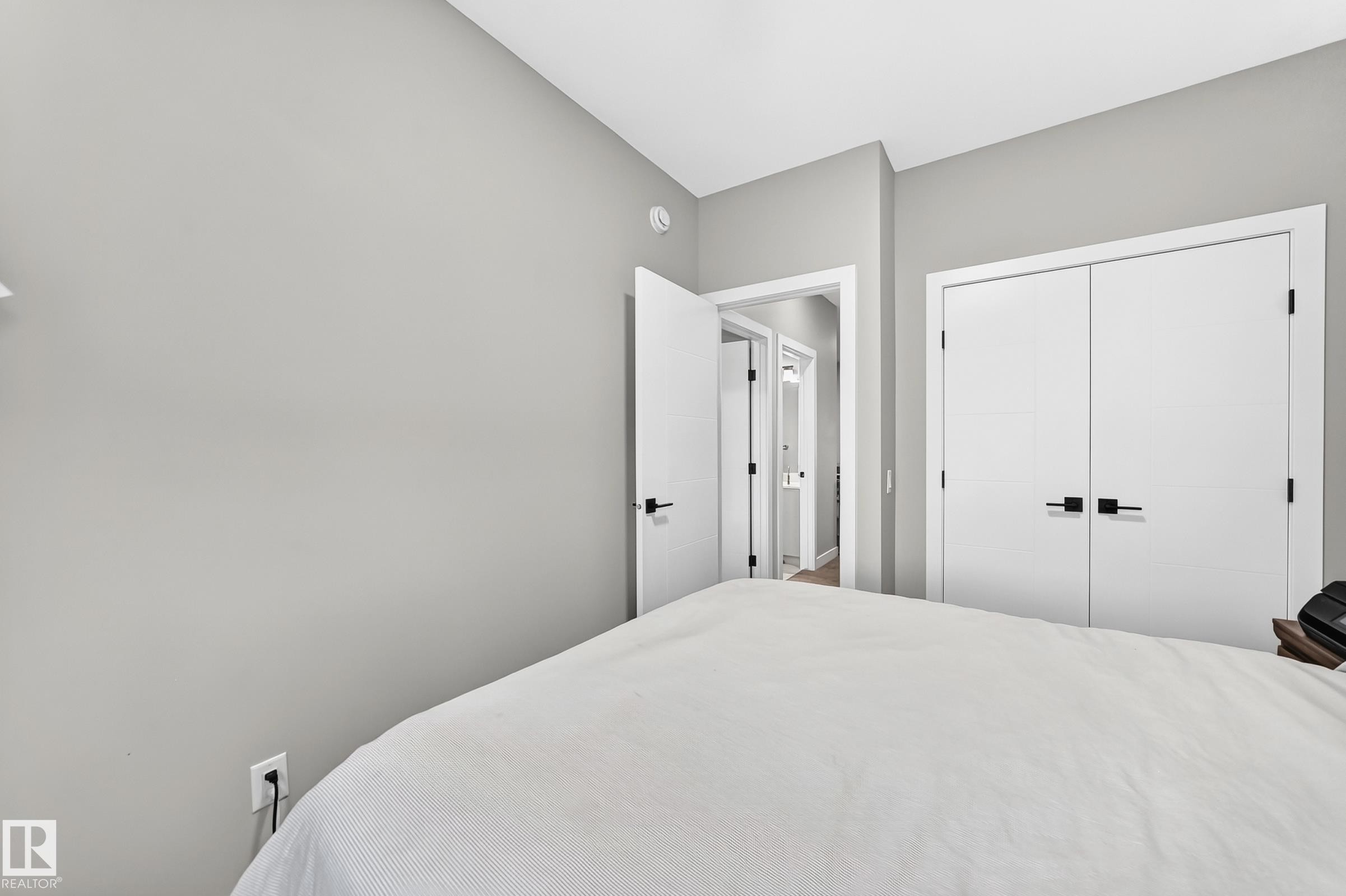 Light gray walls with white trim, a built-in closet with double doors, and black hardware - 2415 194 Street Nw, Edmonton, AB