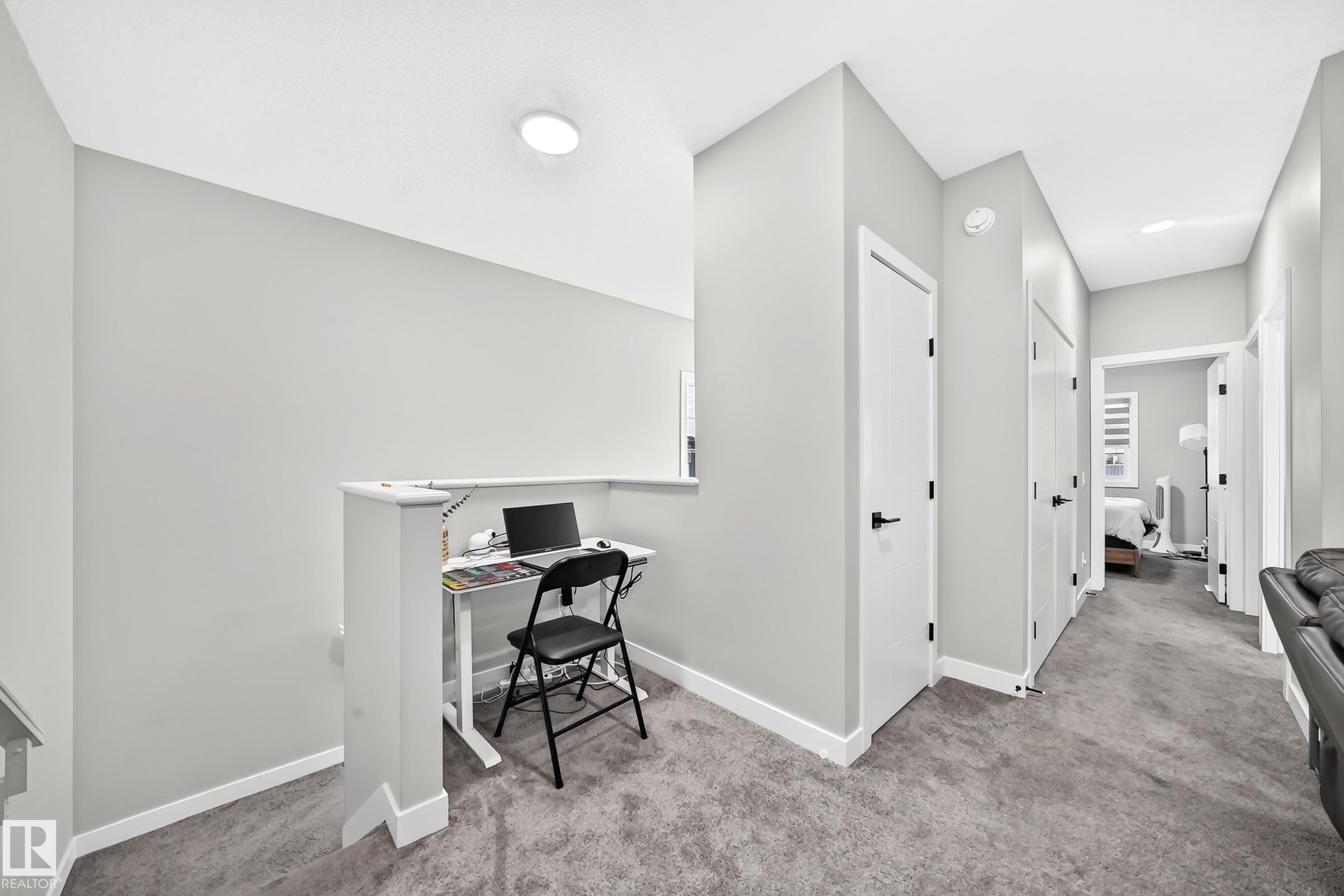 Carpeted hallway with white interior doors, black hardware, and overhead lighting - 2415 194 Street Nw, Edmonton, AB