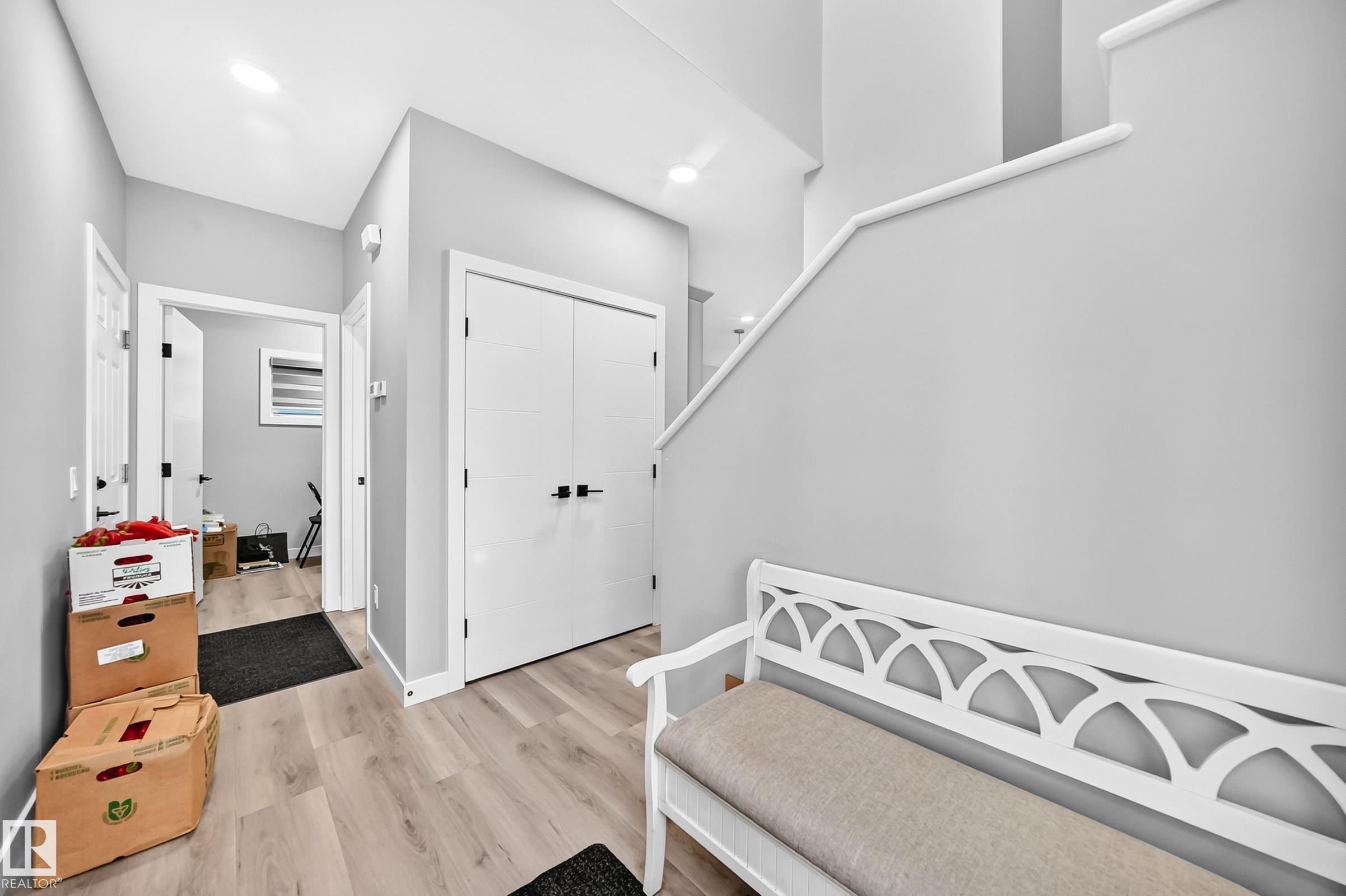 Light wood-finish flooring, white walls, white doors with dark hardware, and recessed ceiling lighting - 2415 194 Street Nw, Edmonton, AB