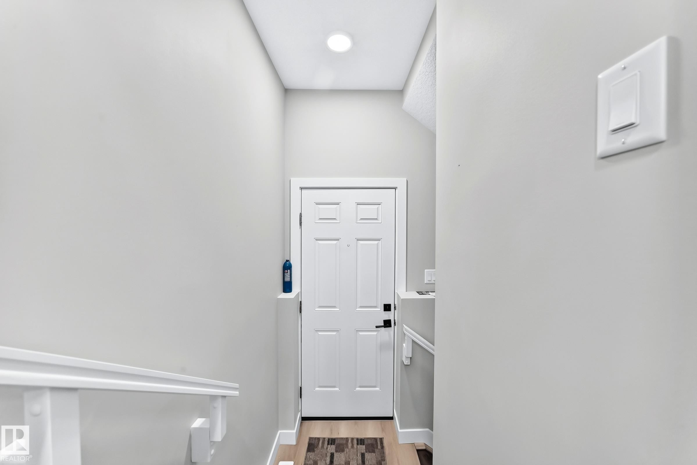 White panel door with black hardware, wood-finish flooring, and recessed ceiling lighting - 2415 194 Street Nw, Edmonton, AB