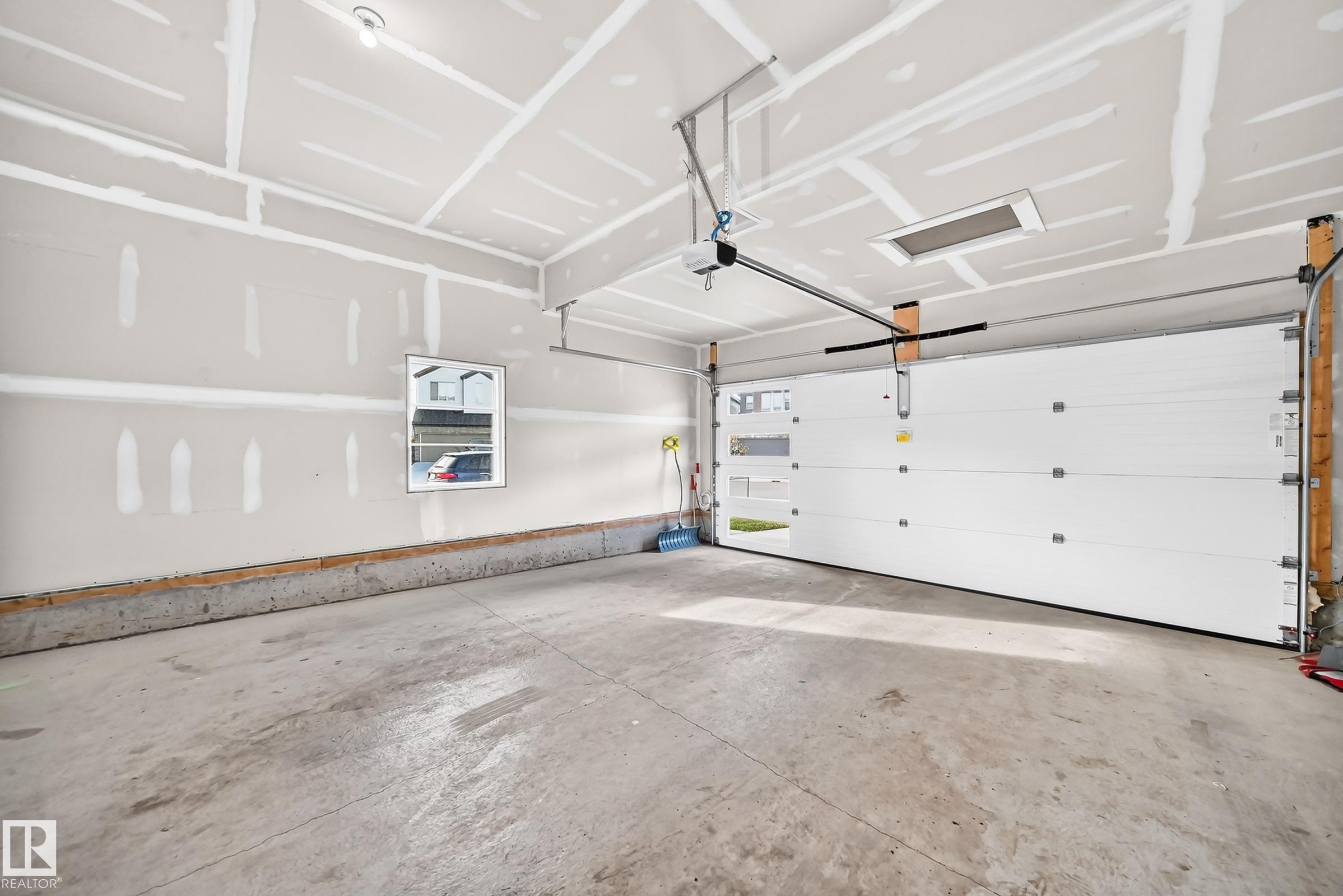 Unfinished interior walls, concrete flooring, automatic garage door opener, overhead lighting, and a single window - 2415 194 Street Nw, Edmonton, AB