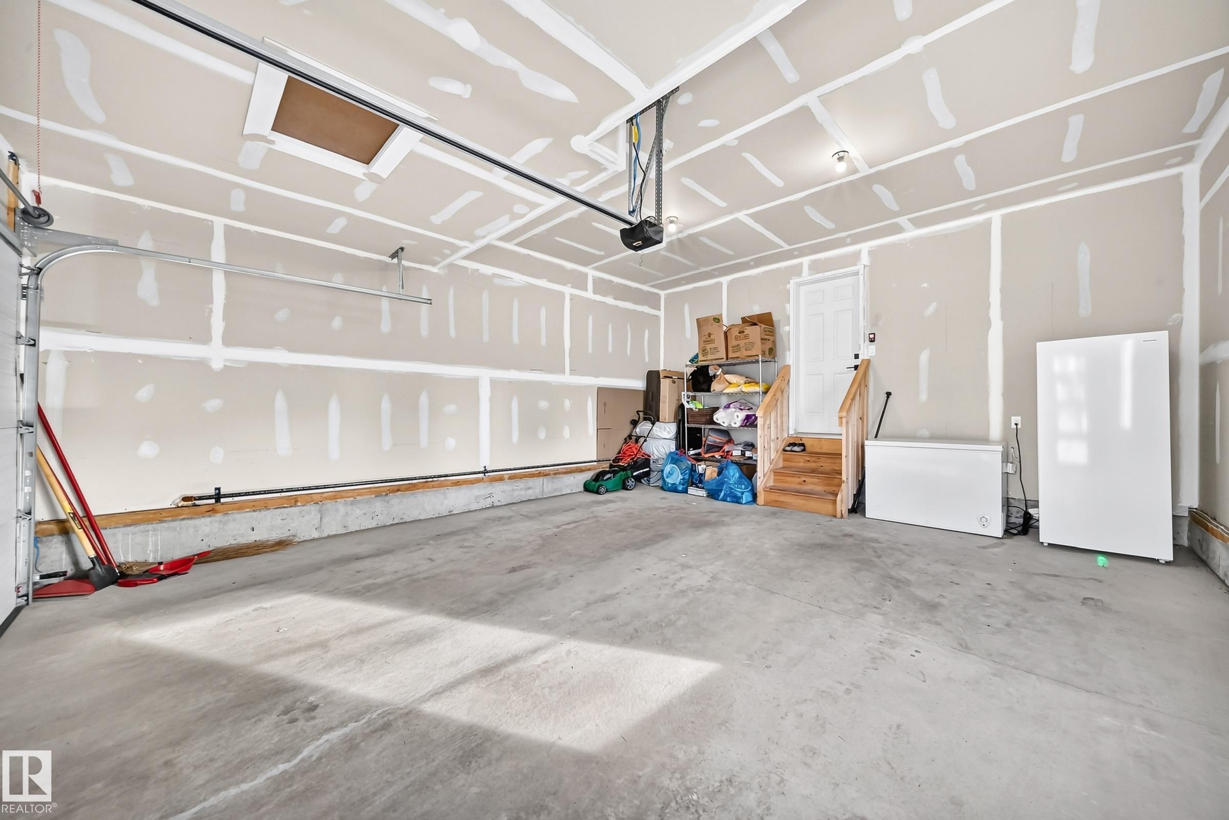 Concrete flooring, overhead garage door system, interior access door, wood-finish stairs - 2415 194 Street Nw, Edmonton, AB