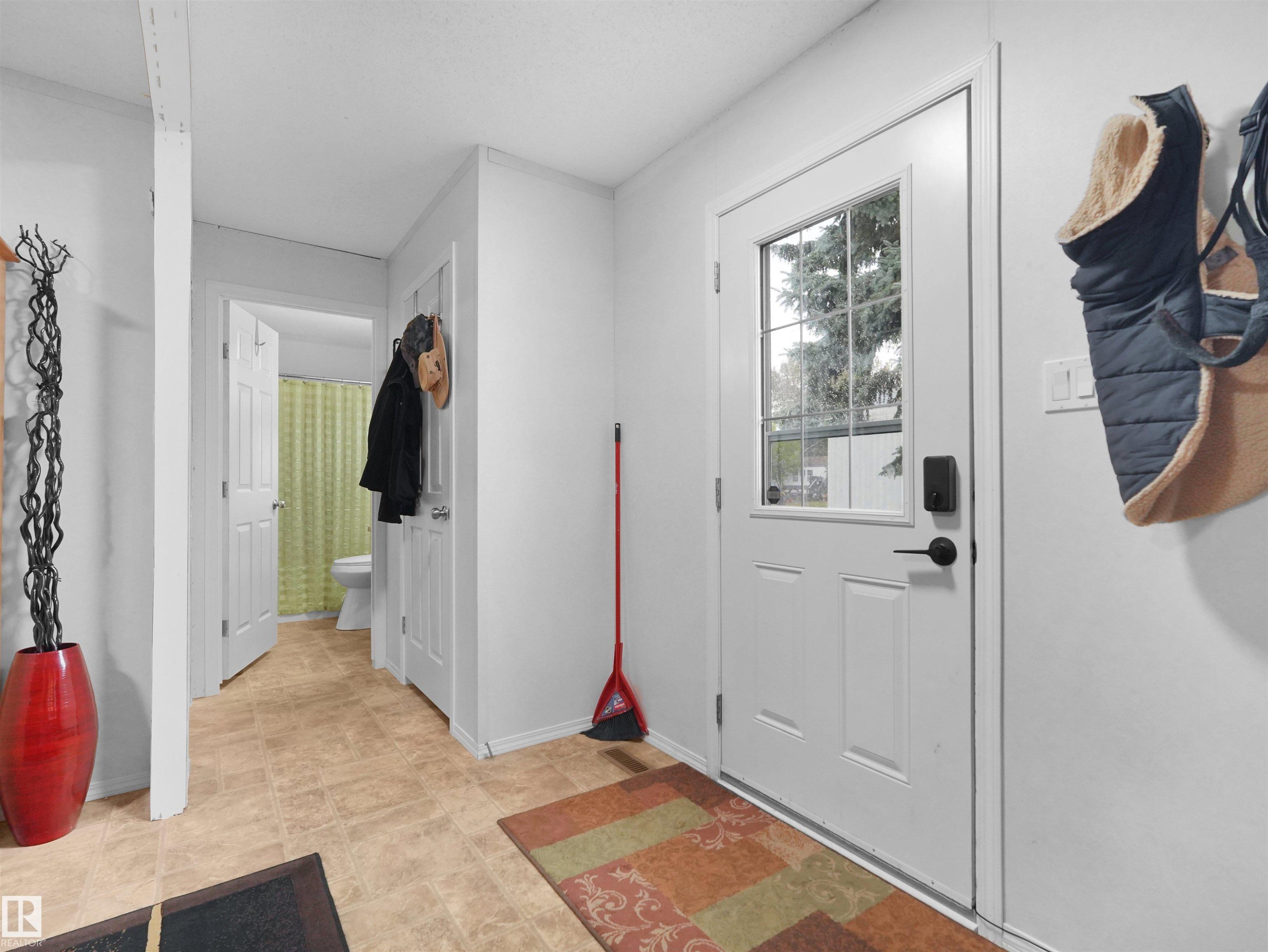 Entryway featuring a white paneled door with a multi-pane glass insert, dark hardware, and light-colored flooring - 52 Evergreen Park Northwest, Edmonton, AB