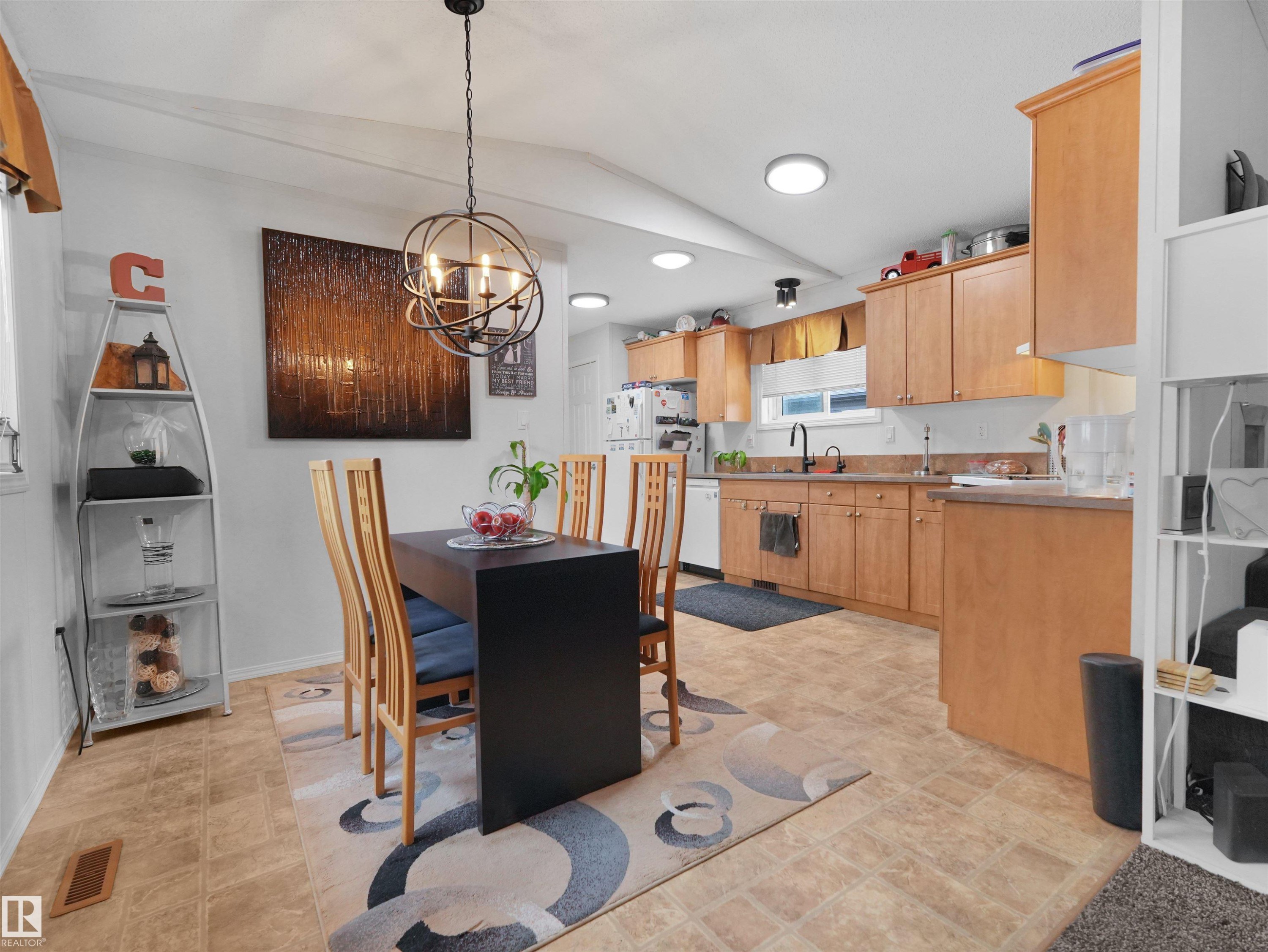 Open-concept kitchen and dining area featuring warm wood-finish cabinetry, a black kitchen faucet, and recessed lighting - 52 Evergreen Park Northwest, Edmonton, AB