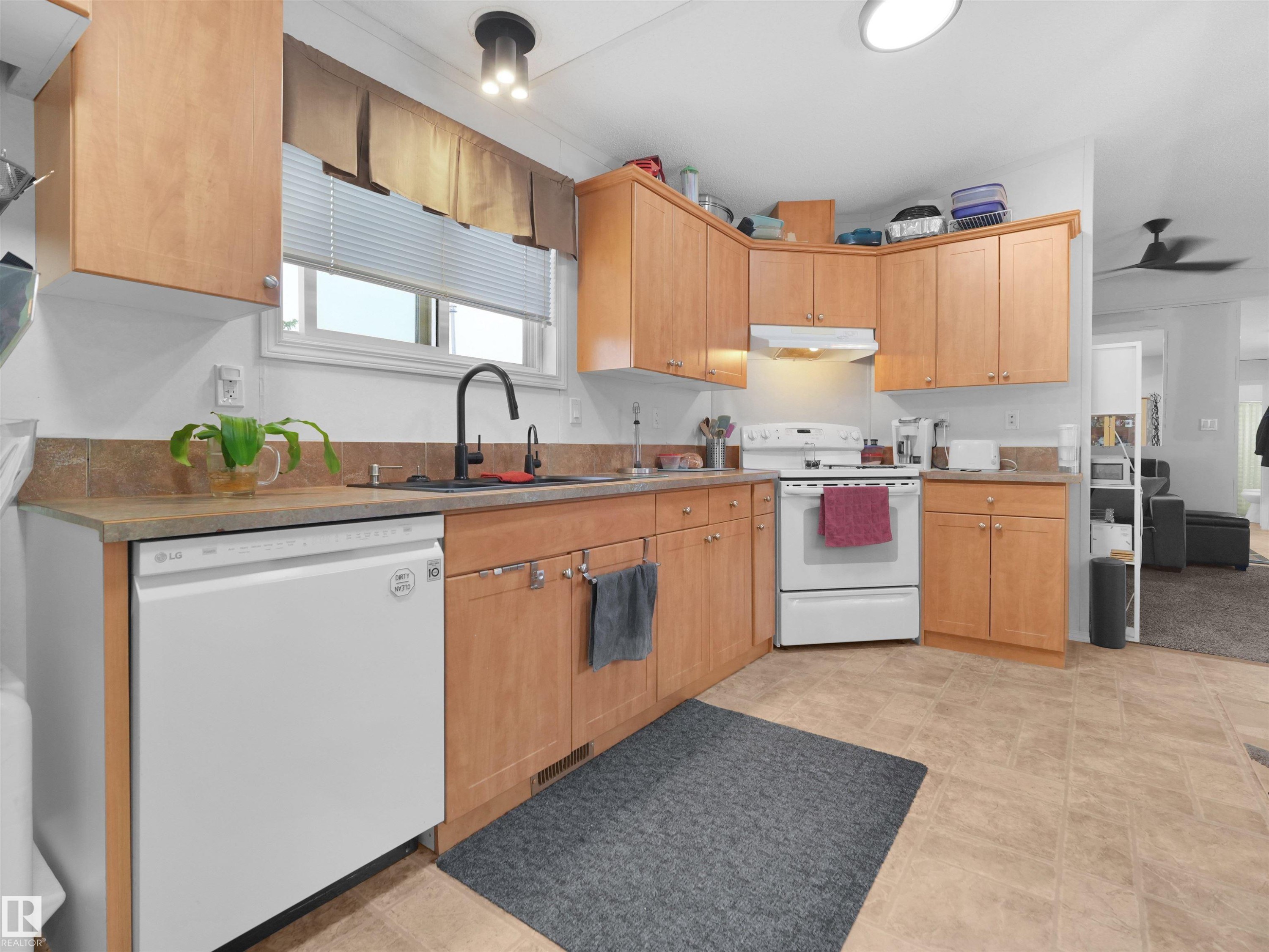 U-shaped kitchen with wood-finish cabinetry, light-toned countertops, and a tile backsplash - 52 Evergreen Park Northwest, Edmonton, AB