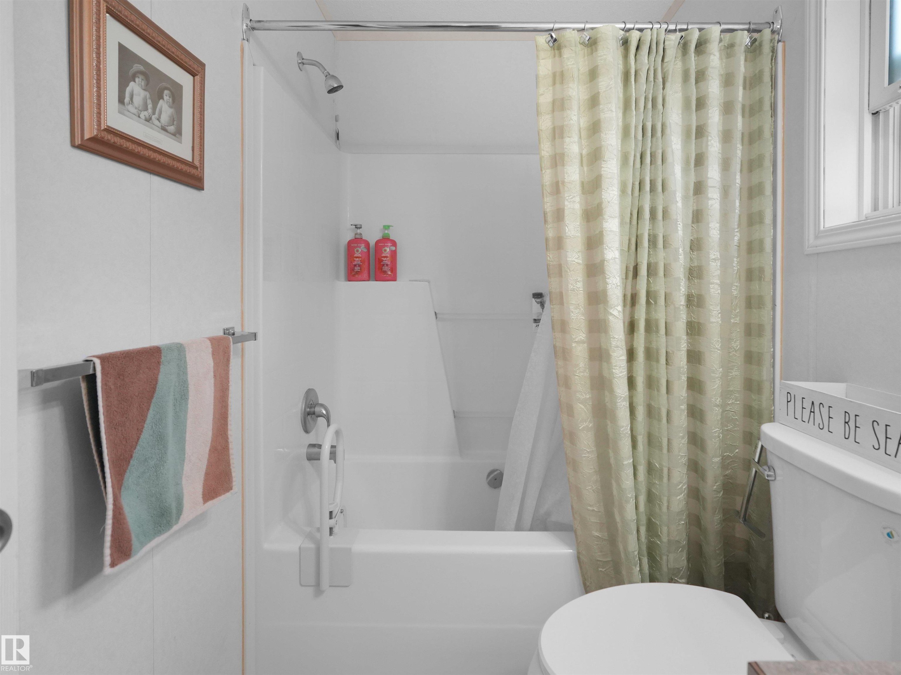 Tub and shower combination with a showerhead and wall-mounted faucet, chrome towel bar, and a window with white trim - 52 Evergreen Park Northwest, Edmonton, AB