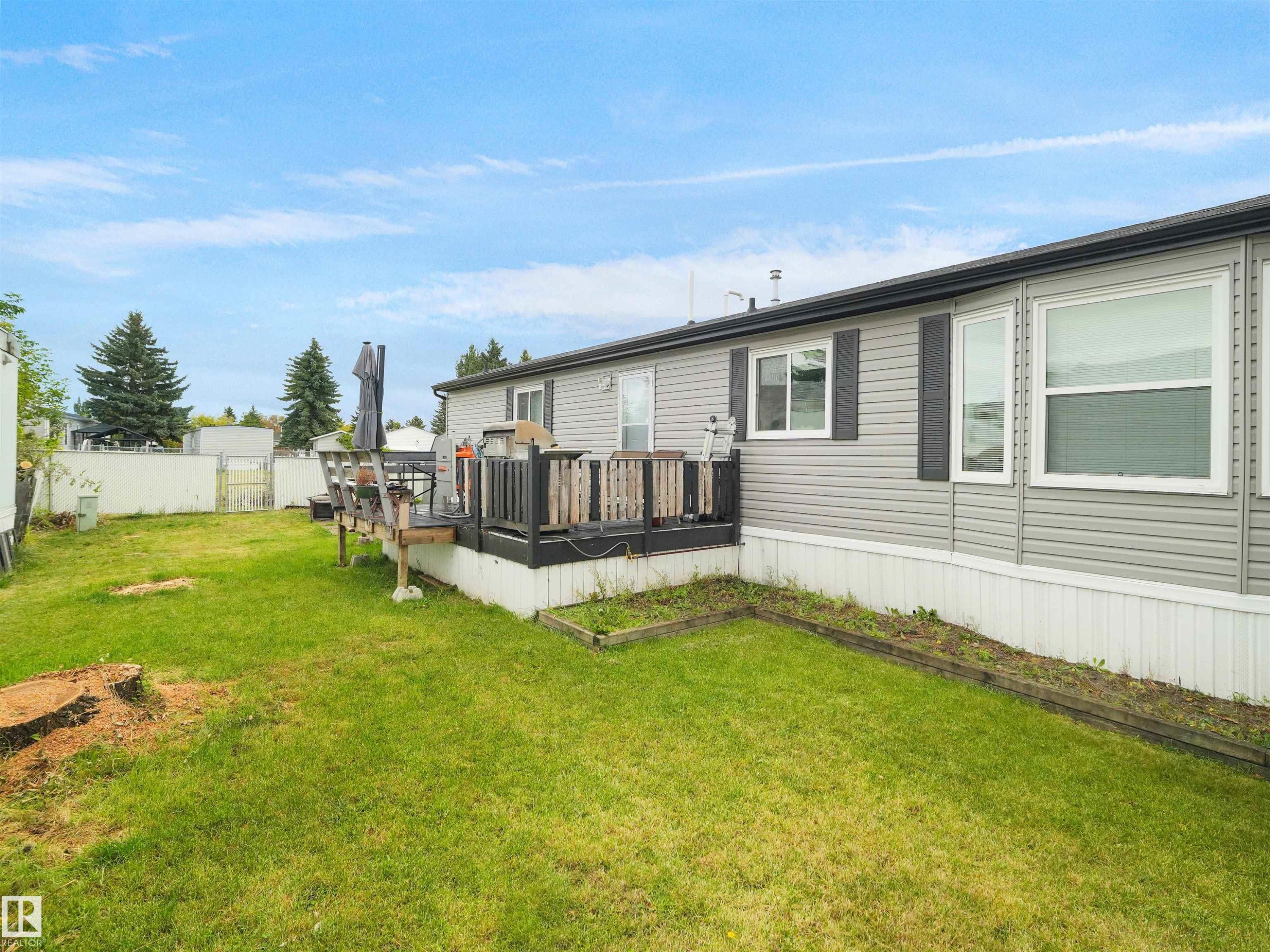 Expansive grassy yard with a multi-level wooden deck featuring a dark railing - 52 Evergreen Park Northwest, Edmonton, AB