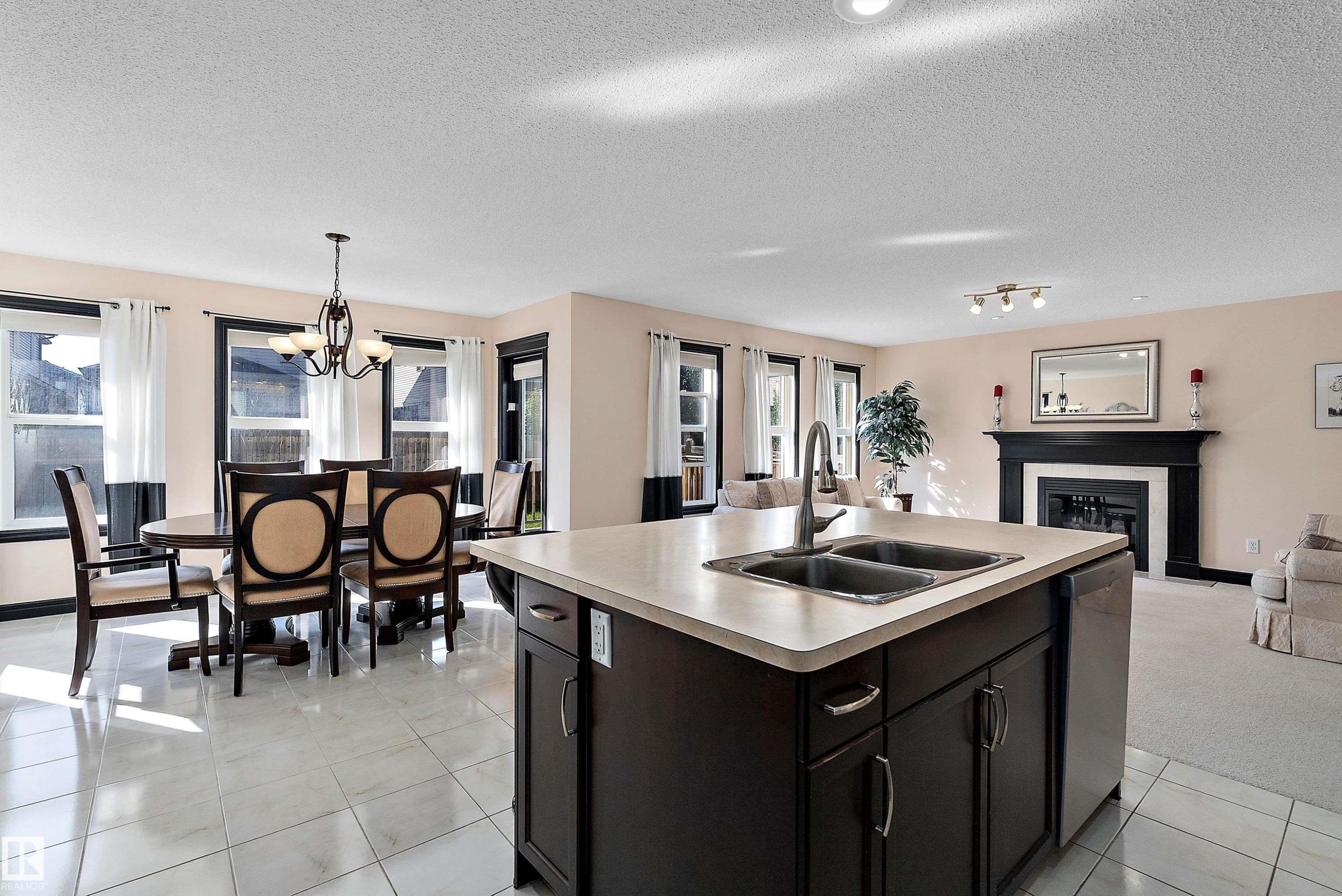 Kitchen island with a double basin sink, dark wood-finish cabinetry, and light-toned countertops - 11515 16 Avenue Sw, Edmonton, AB