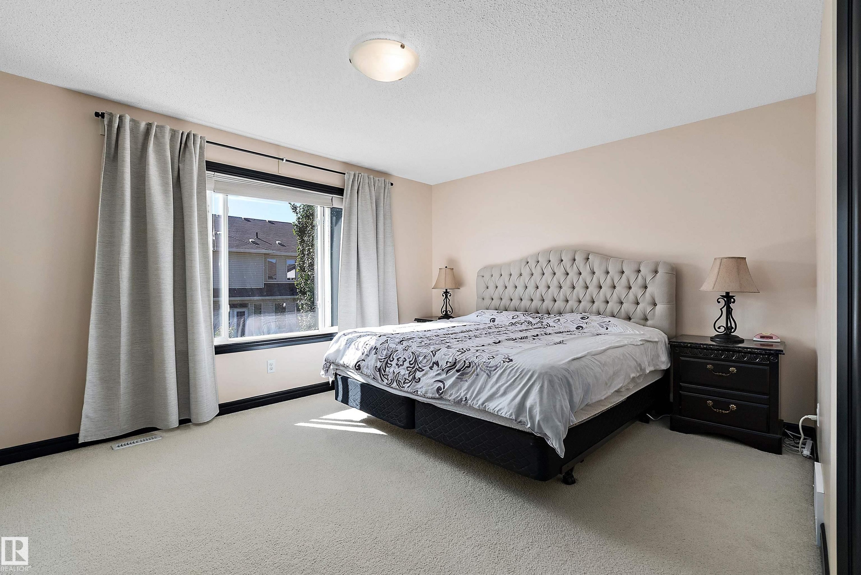 Carpeted room featuring a large window, neutral wall paint, and a flush mount ceiling light fixture - 11515 16 Avenue Sw, Edmonton, AB