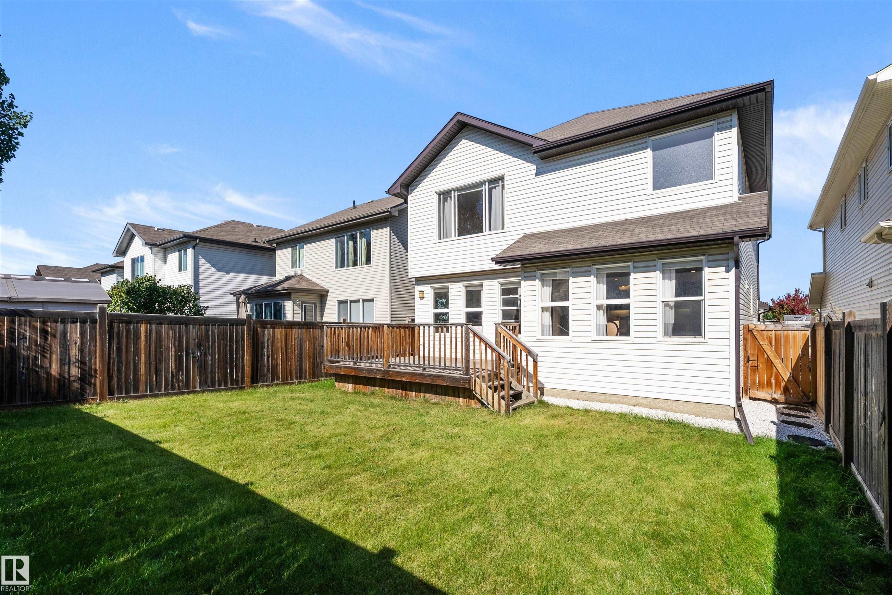 Expansive backyard with a manicured lawn, a multi-level wood deck, and a privacy fence - 11515 16 Avenue Sw, Edmonton, AB