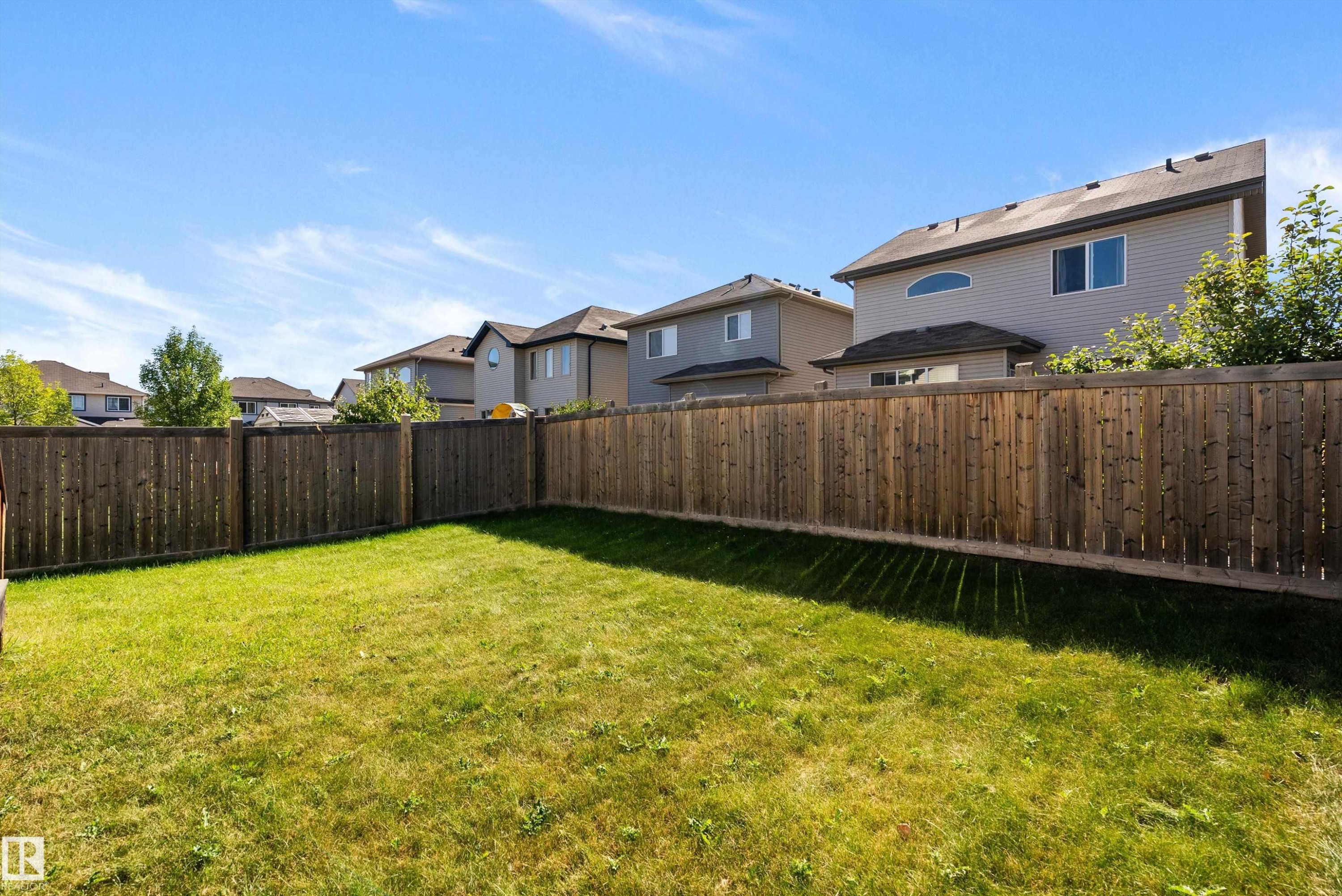 Enclosed backyard featuring a wood privacy fence and a manicured lawn - 11515 16 Avenue Sw, Edmonton, AB