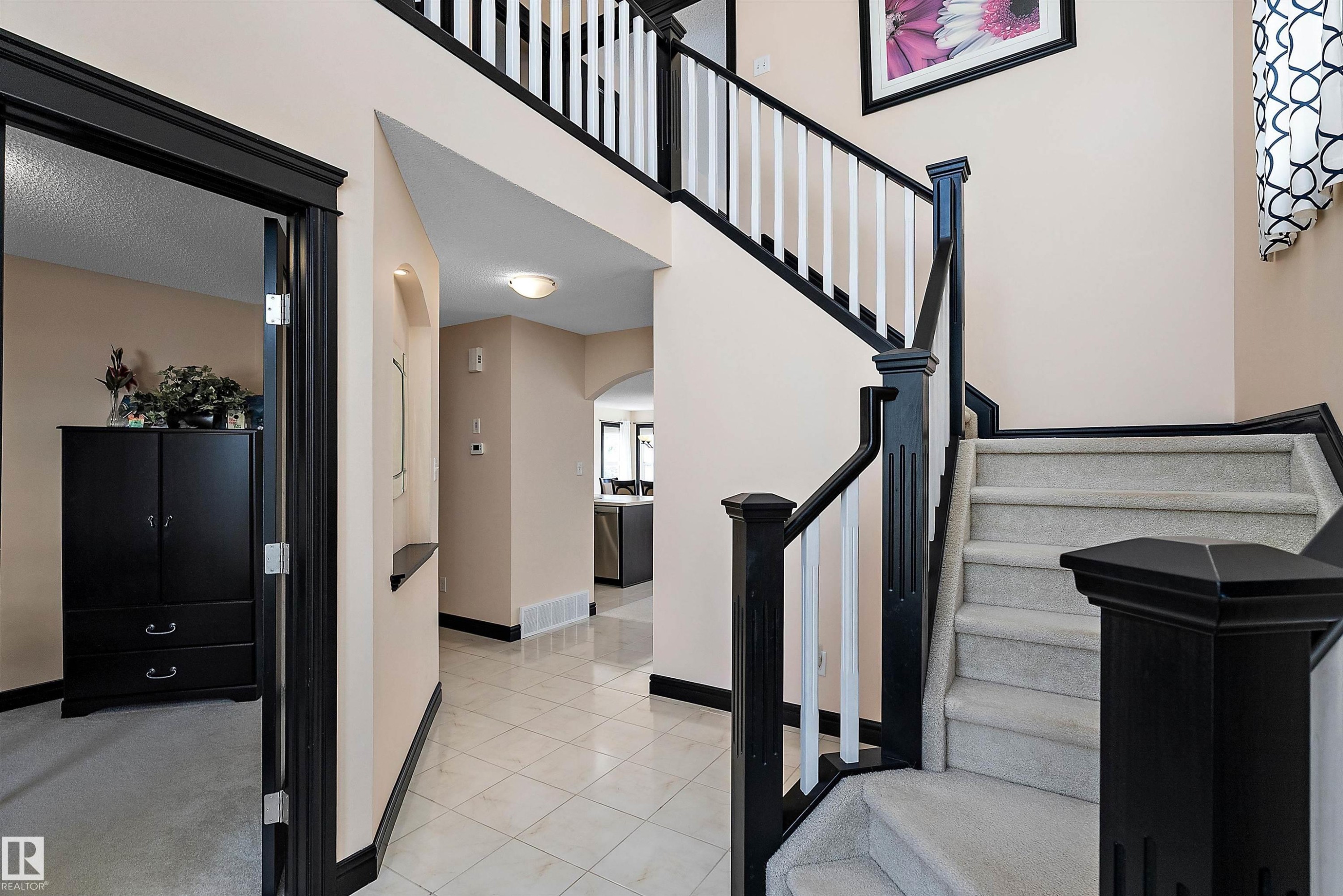 Central staircase featuring dark wood newel posts and handrails with white balusters - 11515 16 Avenue Sw, Edmonton, AB