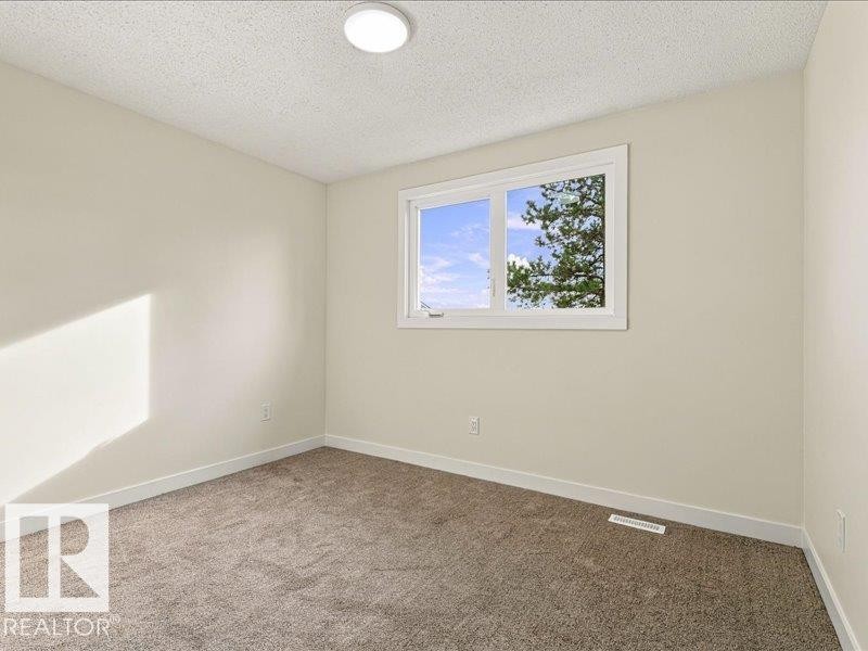 Neutral wall paint, plush carpeting, white trim, and a flush-mount ceiling light fixture - 18325 66 Avenue Nw, Edmonton, AB