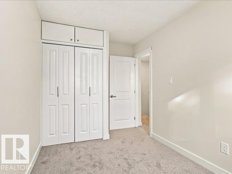 Wall-to-wall carpeting, bi-fold closet doors, integrated upper cabinetry, and a white interior door - 18325 66 Avenue Nw, Edmonton, AB