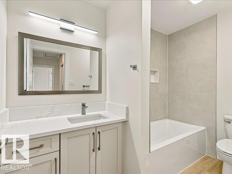 Vanity with a countertop, undermount sink, and wall-mounted mirror - 18325 66 Avenue Nw, Edmonton, AB
