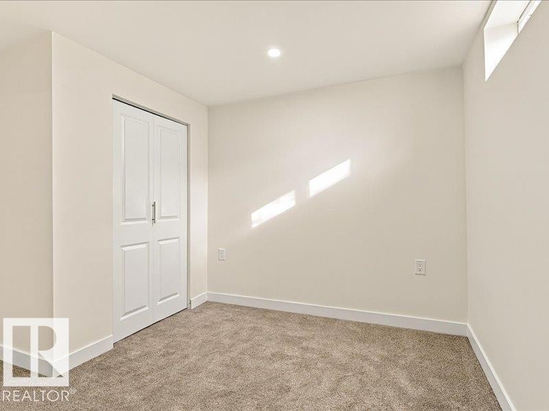 Neutral-toned wall paint with recessed ceiling lighting, carpeted flooring, and a white bi-fold closet door - 18325 66 Avenue Nw, Edmonton, AB