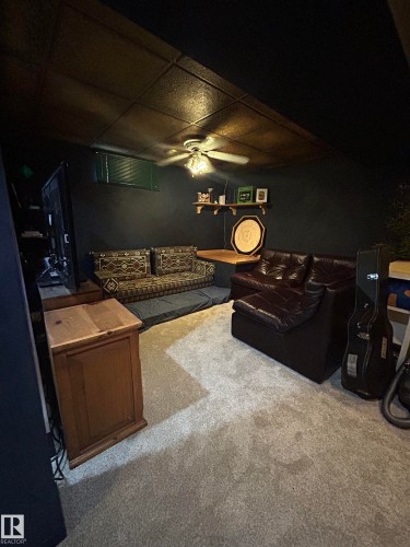 Carpeted flooring, paneled ceiling with ceiling fan, wall-mounted shelving, and a built-in wooden counter - 10678 Beaumaris Road Nw, Edmonton, AB 