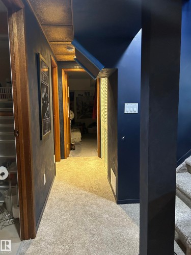 Carpeted hallway with wood-finish door frames and a painted ceiling - 10678 Beaumaris Road Nw, Edmonton, AB 