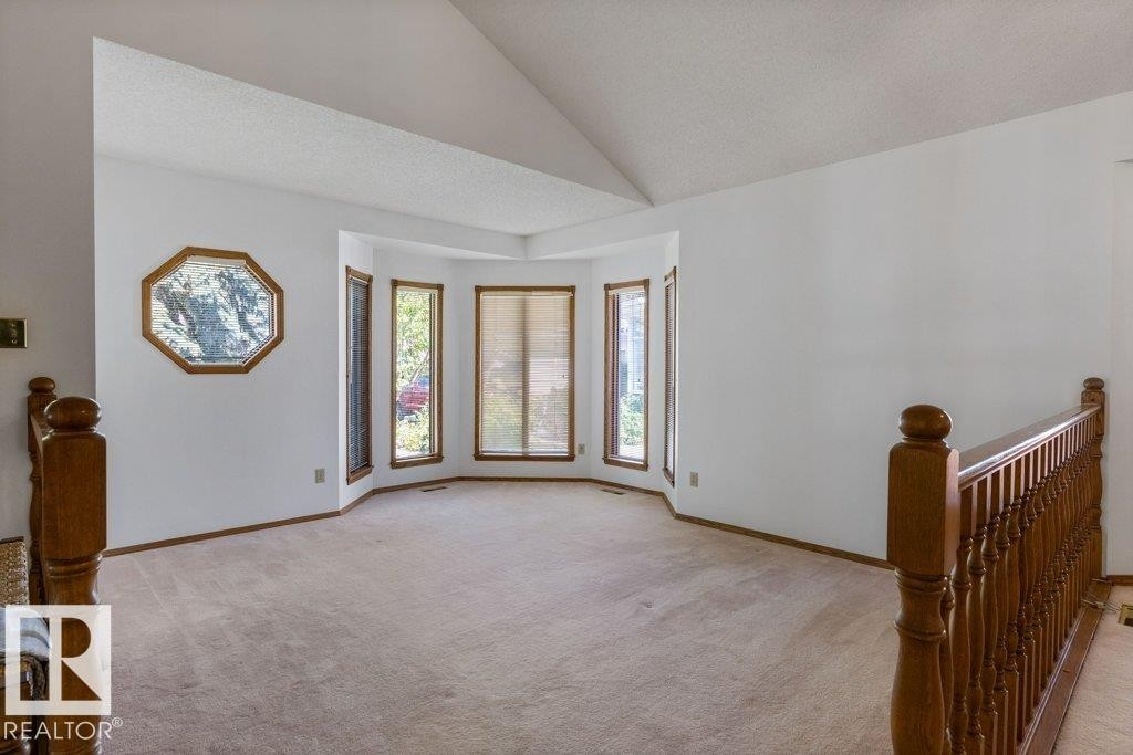 Vaulted ceiling, bay window, light wood window trim, light wood railing, and an octagonal decorative window - 507 Burton Close Nw, Edmonton, AB