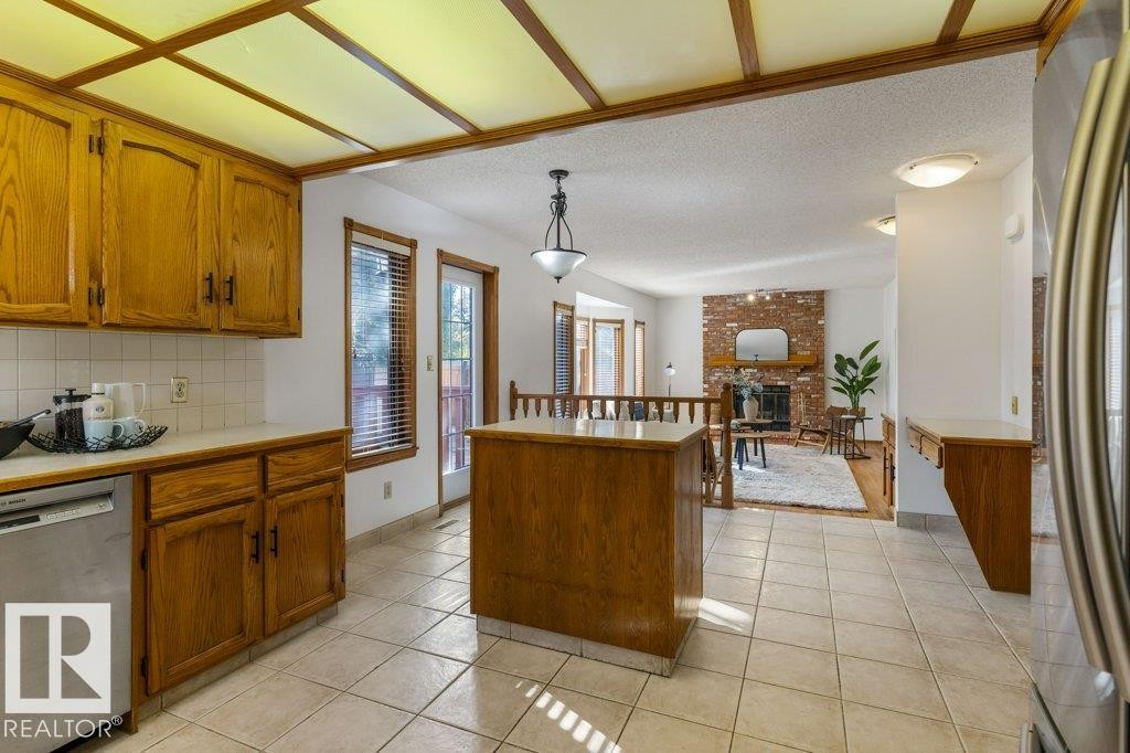 Kitchen featuring a light wood cabinet package, white tile backsplash, and light tile flooring - 507 Burton Close Nw, Edmonton, AB