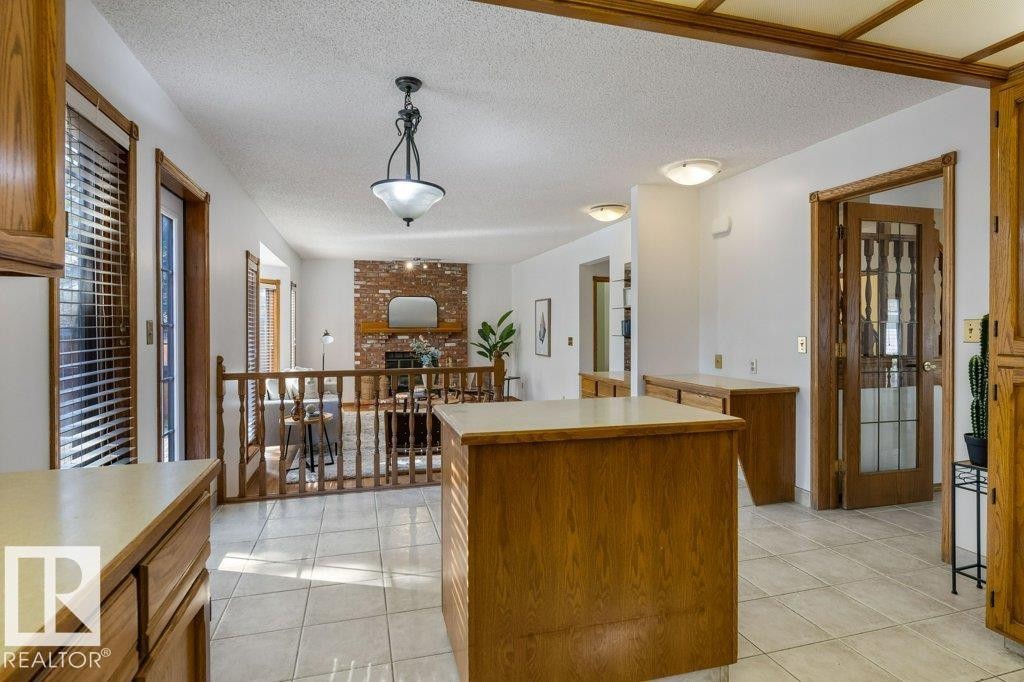 Kitchen featuring wood-finish cabinetry, tile flooring, and a central island - 507 Burton Close Nw, Edmonton, AB