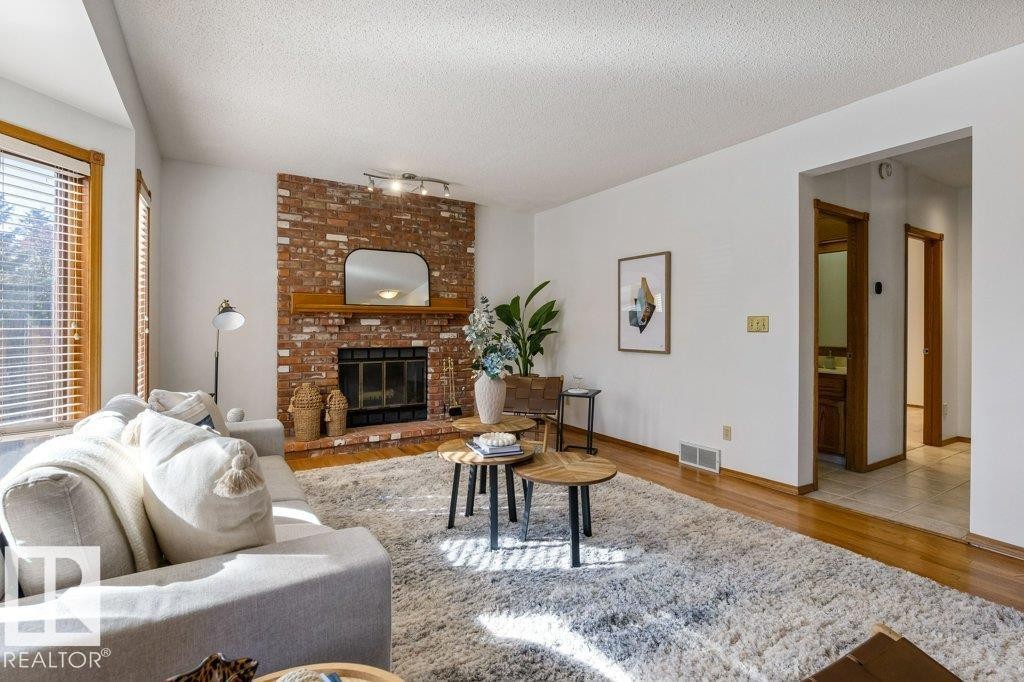 Brick fireplace with wood mantel, hardwood flooring, and neutral wall tones - 507 Burton Close Nw, Edmonton, AB