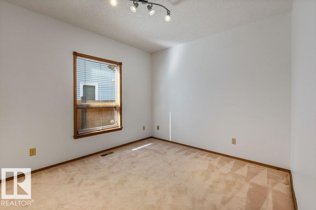 Corner room featuring a single window, track lighting, and carpeted flooring - 507 Burton Close Nw, Edmonton, AB