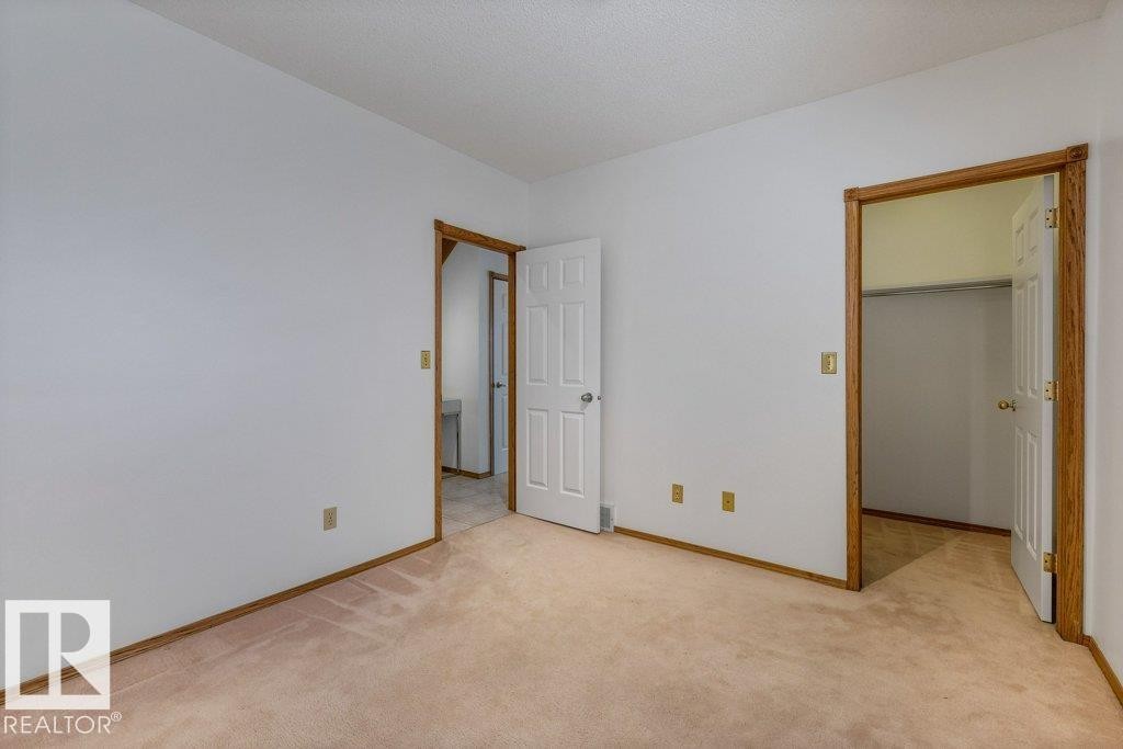 Spacious bedroom with neutral wall finishes, and wood-finish framed doorways - 507 Burton Close Nw, Edmonton, AB