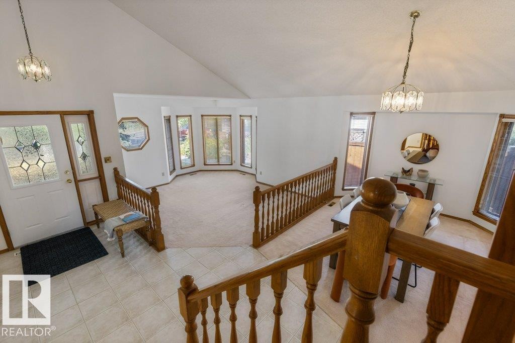 Vaulted ceilings, bay windows, leaded glass entry door, wood-tone trim, and open stair railing - 507 Burton Close Nw, Edmonton, AB