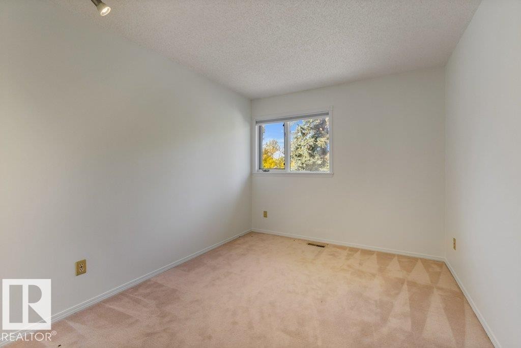 Neutral tone wall paint, track lighting, window with exterior scenery, and carpet flooring - 507 Burton Close Nw, Edmonton, AB