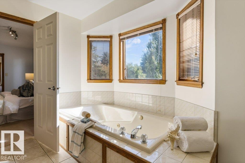 Built-in tub with tile surround, wood-trimmed bay windows, and tile flooring - 507 Burton Close Nw, Edmonton, AB