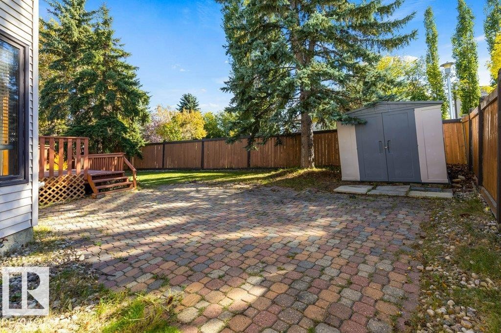 Expansive backyard featuring a wood deck, paver patio, a storage shed, and a wooden fence - 507 Burton Close Nw, Edmonton, AB