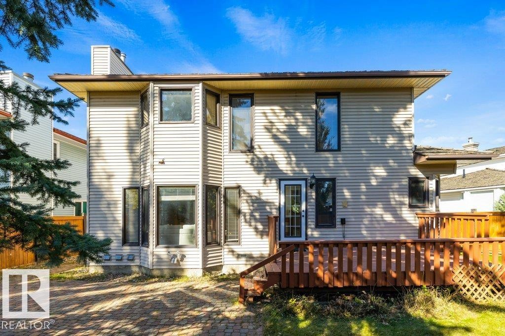 Rear exterior featuring horizontal siding, multiple windows, an exterior door with glass panels, and a wooden deck with railing - 507 Burton Close Nw, Edmonton, AB