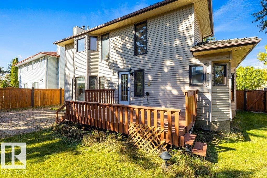 Exterior siding, multi-level wood deck, wood privacy fence, paved driveway, and grass lawn - 507 Burton Close Nw, Edmonton, AB