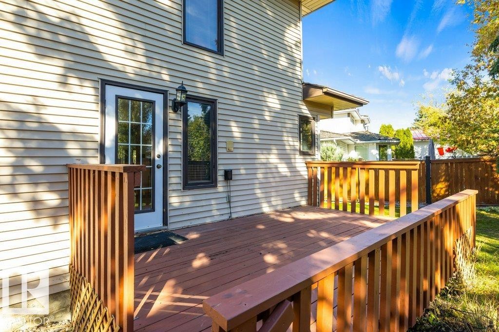 Expansive wooden deck with coordinating railings, exterior siding, and an exterior door with glass inserts - 507 Burton Close Nw, Edmonton, AB