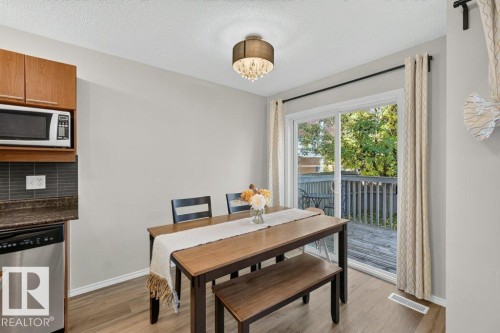 Sliding glass door leading to an outdoor deck, ceiling-mounted light fixture, wood-finish flooring, wood cabinetry, and stainless steel appliances - #41 287 Macewan Rd Sw, Edmonton, AB 