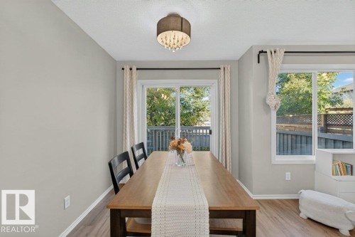 Recessed lighting with a drum shade fixture, light-toned walls, wood-finish flooring, sliding glass door, and large window with natural light - #41 287 Macewan Rd Sw, Edmonton, AB 