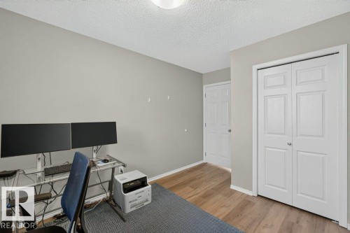 Wood-finish flooring with light gray wall paint, textured white ceiling, and white panel doors - #41 287 Macewan Rd Sw, Edmonton, AB 