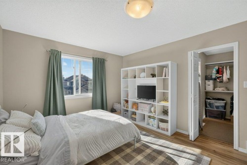 Recessed window with white frame, warm neutral wall paint, wood-finish flooring, and a built-in closet with bifold doors - #41 287 Macewan Rd Sw, Edmonton, AB 